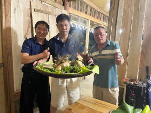 a group of three men holding a plate of food at Hoa Phong homestay Moc Chau in Mộc Châu