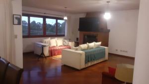 ein Wohnzimmer mit einer weißen Couch und einem Kamin in der Unterkunft Apartamento no Morro do Elefante (Capivari) in Campos do Jordão