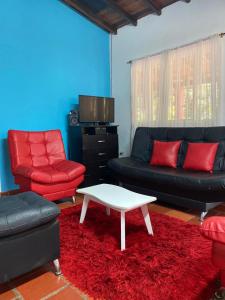 - un salon doté d'un mobilier rouge et noir et d'une table basse dans l'établissement Finca el Paraíso, à San Gil