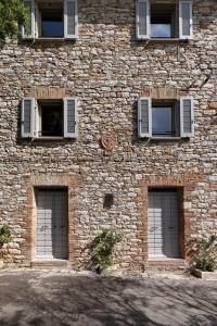 a brick building with three windows and three doors at Forma Your Boutique Suite in Corciano