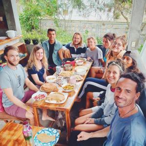 a group of people sitting around a table eating food at Hermanos Perdidos Surf in Las Tunas