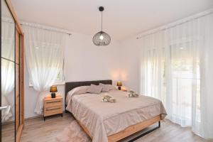 a white bedroom with a large bed and windows at House Tea 2279 in Medulin