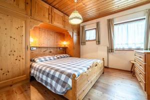 1 dormitorio con 1 cama en una habitación de madera en Tabià La Stua, en Arabba