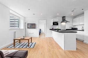 eine weiße Küche und ein Wohnzimmer mit einem Tisch in der Unterkunft London's Charm 2 BR Flat CB3 in Croydon