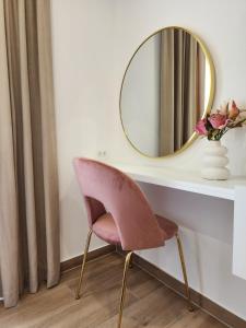 uma cadeira rosa sentada ao lado de uma mesa com um espelho em New Apartment White Angel em Duće