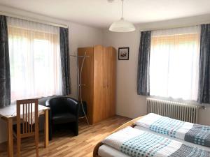 um quarto com 2 camas, uma secretária e uma cadeira em Lasserhof em Aigen im Ennstal