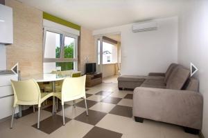 uma sala de estar com uma mesa e cadeiras e um sofá em Daška Apartmani em Njivice