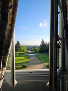 una ventana abierta con vistas a un campo de golf en Château de Craon, en Craon