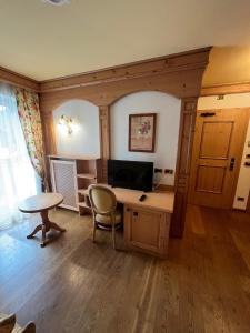 een kamer met een bureau en een tafel en stoelen bij Park Hotel Aurora in Pozza di Fassa