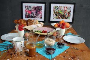 einen Holztisch mit Teller mit Lebensmitteln und Obst in der Unterkunft BnB Maison d'Art Breakfast in the Art Gallery in Ploubazlanec