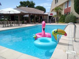 une piscine avec un cygne rose et bleu dans l'eau dans l'établissement ibis Avignon Sud, à Avignon
