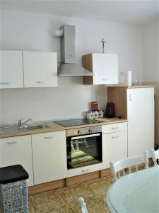 a kitchen with white cabinets and a stove top oven at Cozy place in Dugopolje