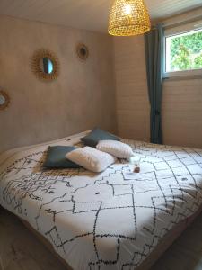 a bedroom with a bed with a black and white comforter at Les Chemins d'Ambre et Thaïs in La Regrippière
