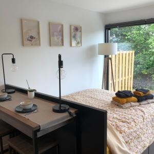 a bedroom with a bed and a table and a window at Au Mas de Mont in Yvoir