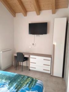 a bedroom with a desk with a tv on the wall at Appartamento Verona in Rovere Veronese