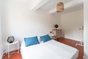 een slaapkamer met een wit bed met blauwe kussens bij La maison d'à côté in Carpentras