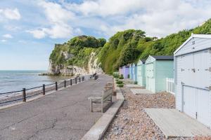 a row of beach huts next to the ocean at Sea Purse - Spectacular house on the beach in Kent