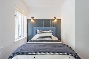 a bed with a blue headboard in a bedroom at Sea Purse - Spectacular house on the beach in Kent