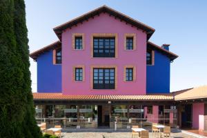 een roze en blauw gebouw met tafels en stoelen bij Globales Playa de Las Llanas in Muros de Nalón