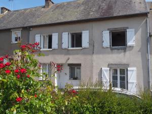 una vecchia casa con finestre bianche e rose rosse di Gîte Location des 4 saisons a Bacilly