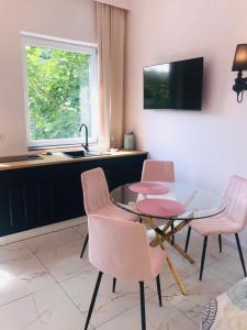 kuchnia ze szklanym stołem i różowymi krzesłami w obiekcie Pokoje Gościnne Bryza Gdynia w mieście Gdynia