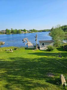 ein Haus auf einem Feld neben einem See in der Unterkunft Bommarvikens Bed & Breakfast in Olofström