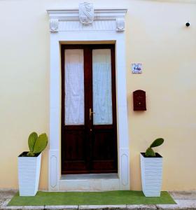 una porta con due piante in vaso davanti di CASA VACANZA NONNA EMMA a Lizzano