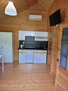 a kitchen with white cabinets and a flat screen tv at Domki i pokoje Linda Zator in Zator