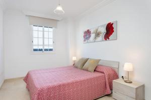 biała sypialnia z łóżkiem z różowym kocem w obiekcie Alojamiento acogedor y tranquilo w mieście La Orotava