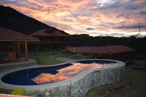 a swimming pool with a rock wall around it at Vistabamba Ecuadorian Mountain Hostel in Vilcabamba