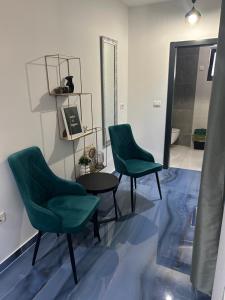 2 sillas verdes y una mesa en una habitación en Boutique Residence Cosmopolis, en Bibinje