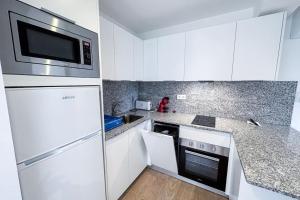 uma cozinha com armários brancos e um micro-ondas em T2F - Best place in Cala-Montgo beach apartment with 2 Beds, Air Conditioning and private Parking em L'Escala