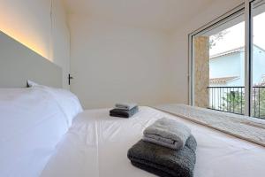 Un dormitorio con una cama blanca con toallas. en T2F - Best place in Cala-Montgo beach apartment with 2 Beds, Air Conditioning and private Parking, en L'Escala