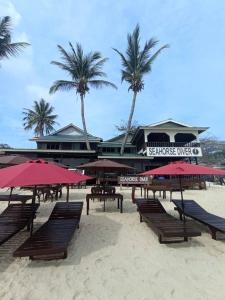 a beach with benches and umbrellas on the sand at Seahorse Diver Guesthouse in Perhentian Islands