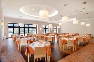 un comedor con mesas, sillas y ventanas en Meteora Hotel at Kastraki, en Kalambaka