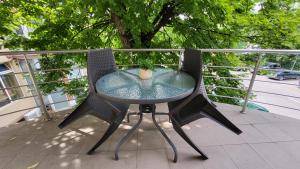 a glass table and two chairs on a balcony at Boutique Global in Braşov