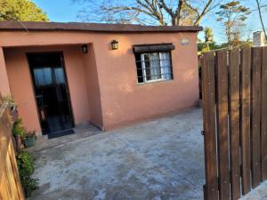 ein kleines rosafarbenes Haus mit einem Tor und einem Zaun in der Unterkunft Las Madres Selvas in Las Toscas