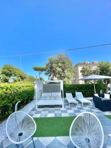 een patio met stoelen en tafels en een parasol bij Hotel Tirreno in Marina di Massa
