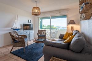 a living room with a couch and a tv at Ziburu Mendi - Appartement Calme, Vue Mer, Parking - WiFi in Ciboure