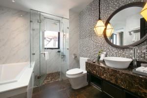 ein Badezimmer mit einem Waschbecken, einem WC und einem Spiegel in der Unterkunft Silkian Hoian Boutique Hotel & Spa in Hoi An