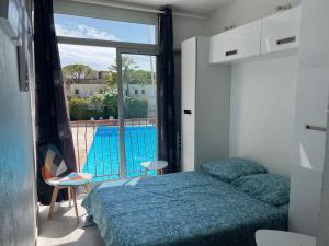 1 dormitorio con cama y vistas a la piscina en Cotépiscine, en Le Lavandou