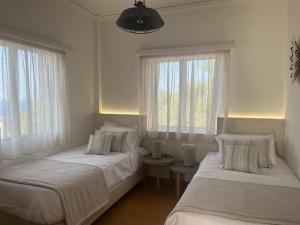 two beds in a room with two windows at Coralina Cottage in Koríthion