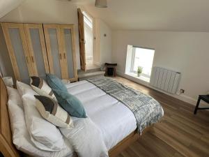 una camera da letto con un grande letto con cuscini e una finestra di Cushendall Stables a Cushendall