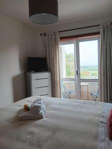 a bedroom with a white bed and a window at Cantinho da Vagueira - Praia in Praia da Vagueira