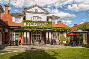 a house with a patio with tables and umbrellas at Pensjonat Zacisze in Plewiska