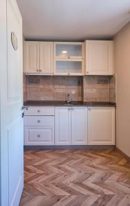 a kitchen with white cabinets and a wooden floor at Meydani Otel in Gokceada Town