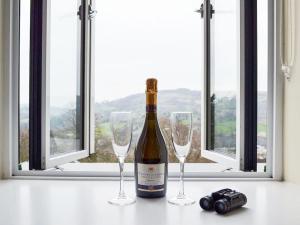 a bottle of wine and two wine glasses on a table at Swallow View, A Spacious Base with stunning views in Matlock