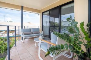 einen Balkon mit Sofa und Tisch und einigen Pflanzen in der Unterkunft Stones Throw To Shelly Beach, Pet Friendly! in Caloundra