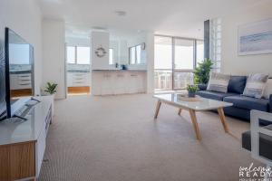 uma sala de estar com um sofá azul e uma mesa em Retro Style Apartment Kings Beach with Ocean Views em Caloundra
