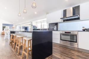 a kitchen with white cabinets and a black counter top at Pet Friendly House Opposite Bokarina Beach in Kawana Waters